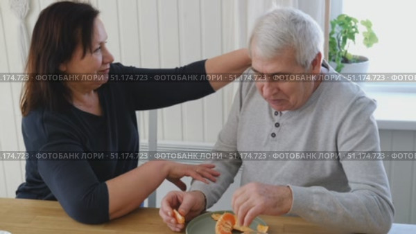 Old couple have breakfast sitting at the kitchen table, drink coffee. Embracing elderly man and woman. Senior couple together marriage in retirement talking with each other. Enjoying the pleasantries. Стоковое видео, видеограф Марина Демидюк / Фотобанк Лори