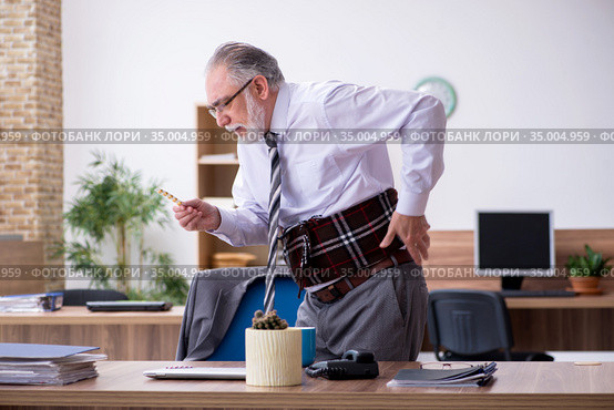 Old male employee suffering from radiculitis at workplace. Стоковое фото, фотограф Elnur / Фотобанк Лори