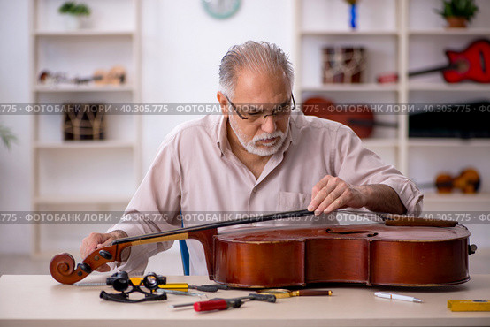 Old male repairman repairing musical instruments at workshop. Стоковое фото, фотограф Elnur / Фотобанк Лори