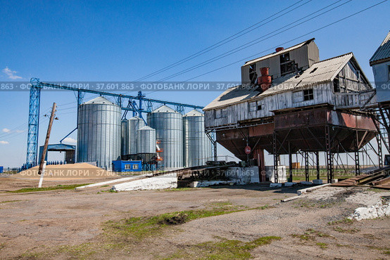 Old Soviet grain storage (right) and modern steel elevator silos (left). Стоковое фото, фотограф Alexey Rezvykh / Фотобанк Лори