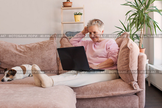 Older smiling 60s woman sitting at home on sofa. Стоковое фото, фотограф Гладских Татьяна / Фотобанк Лори