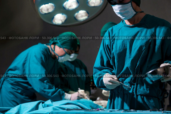Operating room nurse prepare surgical equipment for surgeon doctor with Medical Team Performing Surgical Operation in Operating Room OR. Medical health care Surgery concept. Стоковое фото, агентство Ingram Publishing / Фотобанк Лори