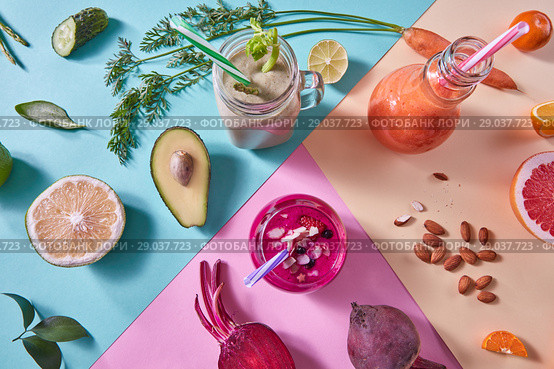 Orange, green and red smoothies from colorful natural vegetables and fruits in a glass bottles with plastic straws on a tricolor background. Top view. Стоковое фото, фотограф Ярослав Данильченко / Фотобанк Лори