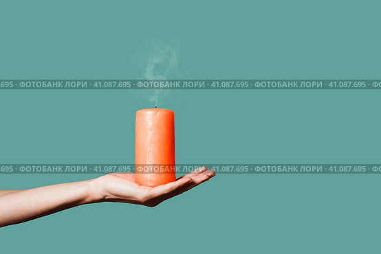 Оранжевая свеча на женской ладони. Рука девушки держит потухшую свечу, изолировано на зеленом фоне. Стоковое фото, фотограф Константин Григорьев / Фотобанк Лори