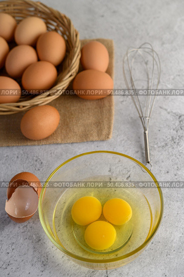 Organic eggs on sack cloth, many eggs on wicker basket and glasses bowl, oil and egg whisk placed on the floor, preparing for cooking food or dessert, copy space. Стоковое фото, агентство Ingram Publishing / Фотобанк Лори