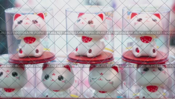 Osaka, Japan - Sep 21 2024, 4k, Close-up view of the statuettes of Maneki-neko cats shaking their heads in the shop window, Osaka, Japan. Стоковое видео, видеограф Сергей Богомяко / Фотобанк Лори