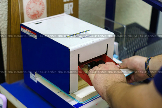 Osaka, Japan - Sep 22 2024, Close up view of the eki stamp, station stamping machine, at JR railway station, with a hands pressing the level, Osaka, Japan. Редакционное фото, фотограф Сергей Богомяко / Фотобанк Лори