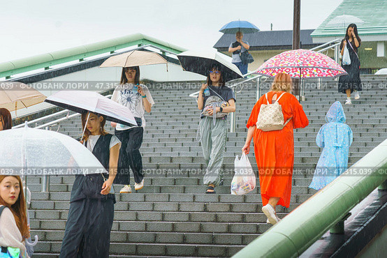 Osaka, Japan - Sep 22 2024, panoramic view of a lot of people with umbrellas going up and down the wide stairs to the Osaka JR ground station, on a rainy day, Osaka, Japan. Редакционное фото, фотограф Сергей Богомяко / Фотобанк Лори