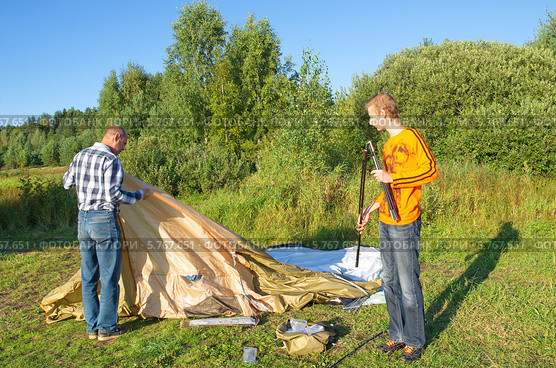Отец с сыном устанавливают туристическую палатку на природе (2013 год). Редакционное фото, фотограф Елена Коромыслова / Фотобанк Лори