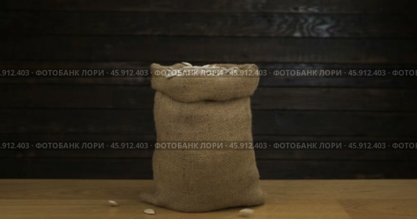 Открытый классический джутовый мешочек, наполненный рассыпающимися тыквенными зернами. Семена в мешочке на деревянном столе. Крупный план. Стоковое видео, видеограф Александр Собко / Фотобанк Лори