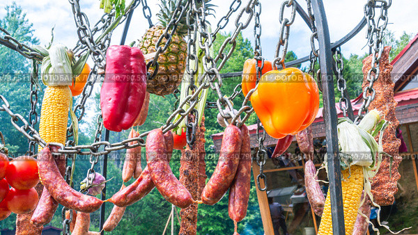 Овощи и мясные продукты готовятся на костре. Колбаса и свежие овощи подвешены на цепочке над грилем. Еда на открытом воздухе. Пикник в выходные. Стоковое фото, фотограф Эдуард Белкин / Фотобанк Лори