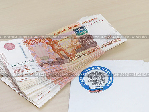 Пачка денег лежит на письме от налоговой службы (2024 год). Редакционное фото, фотограф Татьяна Т / Фотобанк Лори