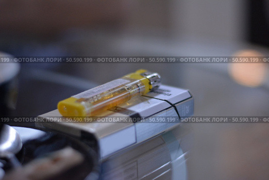 Pack of cigarettes and lighter on the glass table. Стоковое фото, агентство Ingram Publishing / Фотобанк Лори