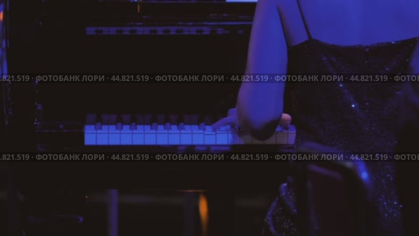 Пальцы пианиста легко скользят по клавишам. Сцена залита холодным голубым светом. Женщина за роялем сидит спиной к камере. Стоковое видео, видеограф Воловодов Владимир / Фотобанк Лори