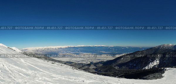 Panoramic view from the top of Pirin mountains to the Bansko city in Bulgaria. Cold winter day, snowy peaks and clear blue sky. Стоковое фото, агентство Ingram Publishing / Фотобанк Лори