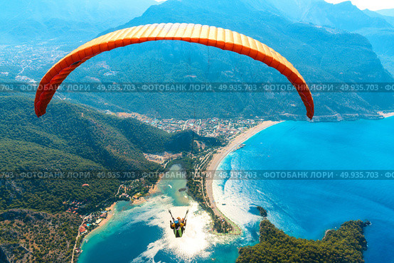 Paragliding in the sky. Paraglider tandem flying over the sea with blue water and mountains in bright sunny day. Aerial view of paraglider and Blue Lagoon in Oludeniz, Turkey. Extreme sport. Landscape. Paraglider tandem flying over the sea with blue water and mounta. Стоковое фото, агентство Ingram Publishing / Фотобанк Лори