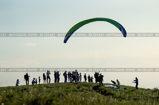 Парапланерист взлетает с вершины горы. A paraglider takes off from the top of a mountain. (2018 год). Редакционное фото, фотограф Евгений Романов / Фотобанк Лори