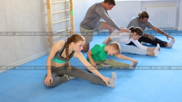 Parents with children family perform warm-up exercises and legs stretching. Стоковое видео, видеограф Яков Филимонов / Фотобанк Лори