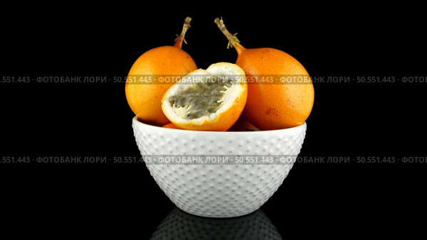 Passion fruit maracuja granadilla on ceramic white bowl, black background. Стоковое фото, агентство Ingram Publishing / Фотобанк Лори