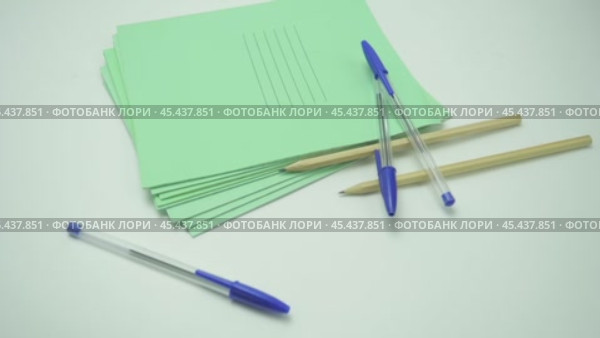 Pens and pencils fall from above on a pack of green school notebooks, isolates on a white background. Стоковое видео, видеограф Дмитрий Нечаев / Фотобанк Лори