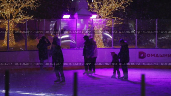 People skate in the evening on a lighted ice rink. A blizzard is raging and snow is falling. Zelenograd, Russia 28.01.2022. Редакционное видео, видеограф Юрий Поздников / Фотобанк Лори