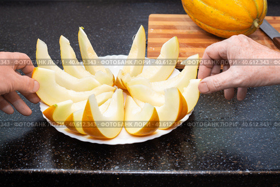 People take sliced ripe juicy melon slices from the plate with their hands. Delicious healthy food. Стоковое фото, фотограф Коханова Наталья / Фотобанк Лори