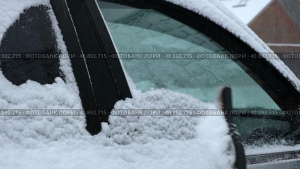 Person brushing fresh snow from car windows after snow storm blizzard. Morning routine difficulties of car owners in cold winter weather. Car window cleaning. Winter season. White snow. Vehicle care. Стоковое видео, видеограф Марина Демидюк / Фотобанк Лори