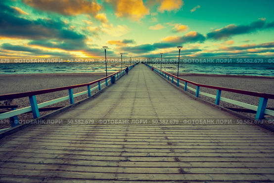 Perspective view of wooden pier over sea. Palanga city at sunset in autumn, Lithuania. Стоковое фото, агентство Ingram Publishing / Фотобанк Лори