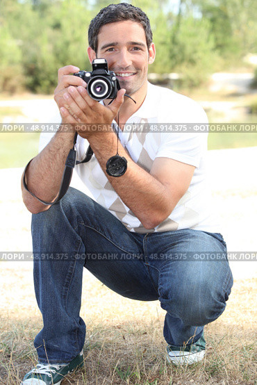 Photographer crouching in the countryside. Стоковое фото, агентство Ingram Publishing / Фотобанк Лори