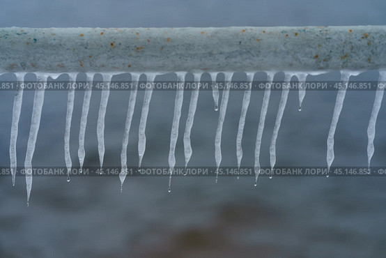 Photography of icicles hang on the roof top.Concept of the beauty in nature. Transparent natural material. Natural cold background. In the city it is life threatening. Falling icicles - threat to life. Стоковое фото, фотограф YuryKara / Фотобанк Лори