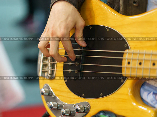 Photography of the musician plays the bass guitar. He picks the strings, clamps the strings on the fretboard. Стоковое фото, фотограф YuryKara / Фотобанк Лори
