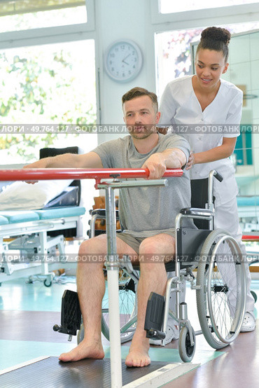 physiotherapist helping man in wheelchair doing exercises. Стоковое фото, агентство Ingram Publishing / Фотобанк Лори