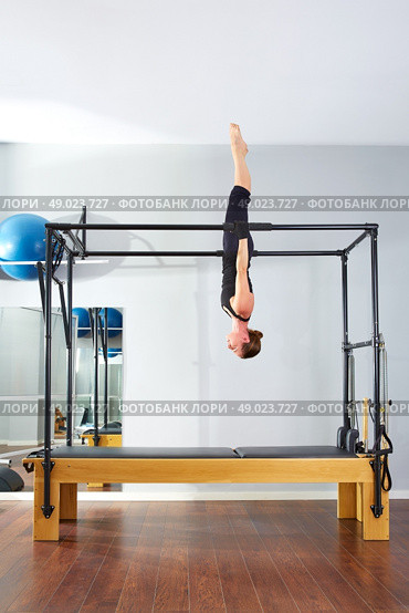 Pilates woman in cadillac acrobatic upside down balance reformer exercise at gym. Стоковое фото, агентство Ingram Publishing / Фотобанк Лори