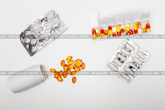 Pillbox by days of the week with fish oil and various pills, capsules and jars scattered on a white background, top view. Стоковое фото, фотограф Кашапова Эльвира / Фотобанк Лори