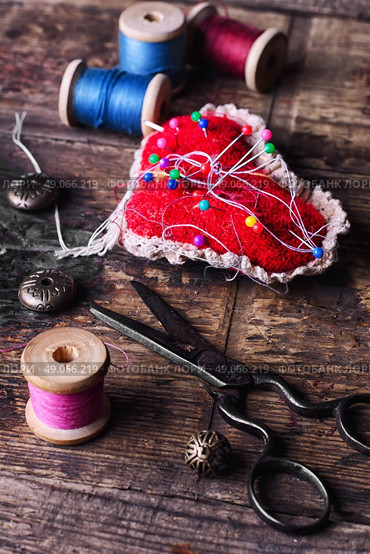 pin cushion with needles,thread and buttons for sewing on stylish wooden background. Стоковое фото, агентство Ingram Publishing / Фотобанк Лори