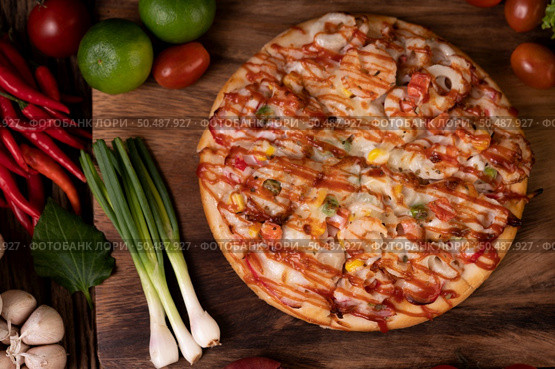 Pizza with sausage, corn, beans, shrimp and bacon on a wooden plate. Стоковое фото, агентство Ingram Publishing / Фотобанк Лори