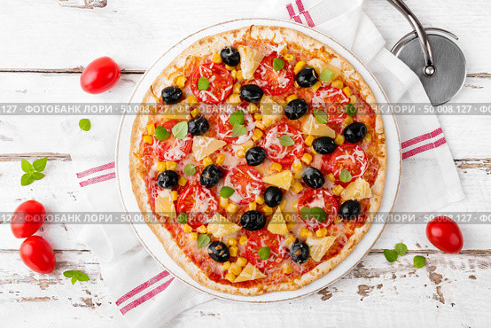 Pizza with tomatoes, mozzarella cheese, olives, corn and basil. Traditional italian cuisine. Top view. Стоковое фото, агентство Ingram Publishing / Фотобанк Лори