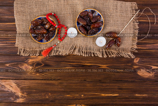 plate juicy dates with red prayer beads lighted candle wooden desk. Стоковое фото, агентство Ingram Publishing / Фотобанк Лори
