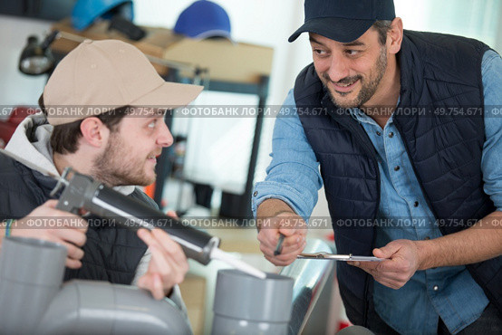 plumber applying adhesive to assemble plumbing pipework. Стоковое фото, агентство Ingram Publishing / Фотобанк Лори