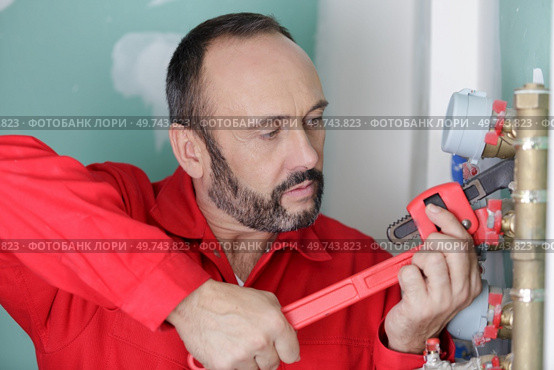 plumber assembles a new water connection to the sink. Стоковое фото, агентство Ingram Publishing / Фотобанк Лори