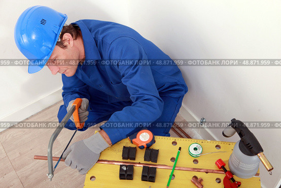 Plumber cutting copper pipe. Стоковое фото, агентство Ingram Publishing / Фотобанк Лори