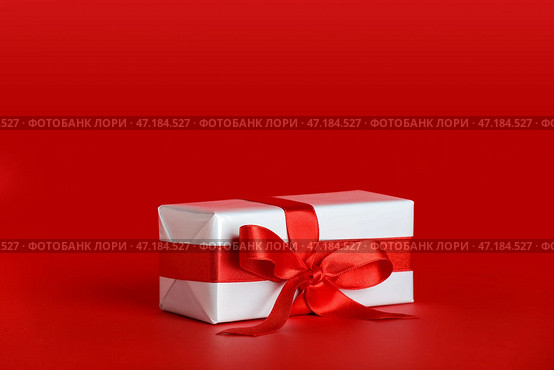 Подарочная коробка с красивым бантом на красном фоне. Празднование Дня святого Валентина. Стоковое фото, фотограф Pixel_shot / Фотобанк Лори