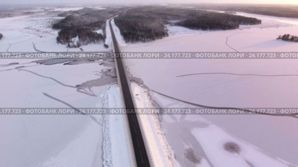 Подъем камеры над зимней автомобильной дорогой, проходящей по мосту через замерзшую реку. Карелия. Стоковое видео, видеограф Кекяляйнен Андрей / Фотобанк Лори