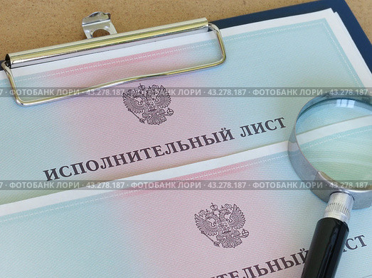 Поиск должника. Лупа лежит на исполнительных листах на принудительное удержание задолженности. Стоковое фото, фотограф Татьяна Т / Фотобанк Лори