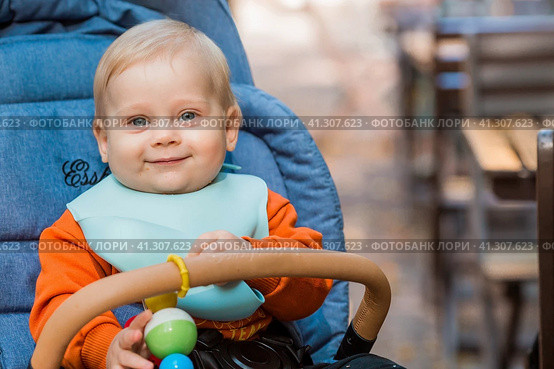 Portrait of a little boy 9 months old in the open air. A happy child in an autumn park is sitting in a stroller. Happy childhood and motherhood. Стоковое фото, фотограф Photojuli / Фотобанк Лори