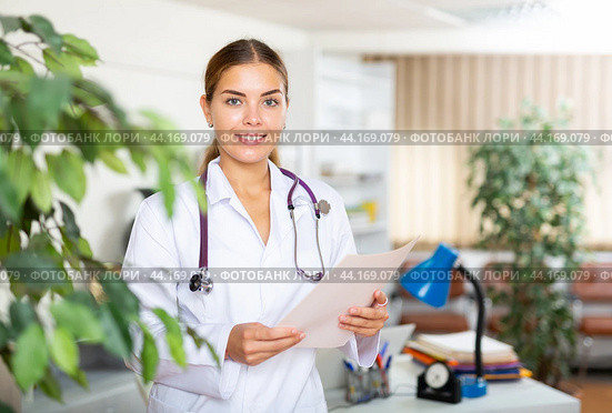 Portrait of a young woman doctor in a office, holding an outpatient patient card in her hands. Стоковое фото, фотограф Яков Филимонов / Фотобанк Лори