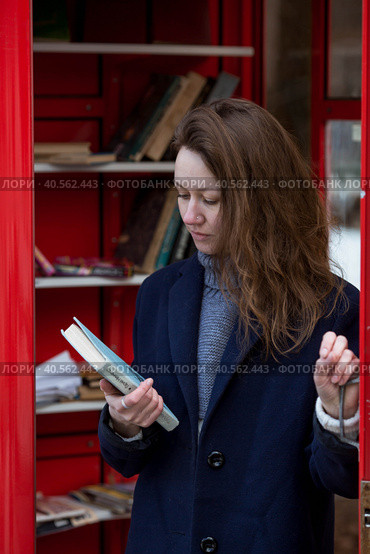 Portrait of a young woman over 30 years old with a book in her hands, a girl took a book from a street library. Modern lifestyle, reading books and education. Стоковое фото, фотограф Photojuli / Фотобанк Лори
