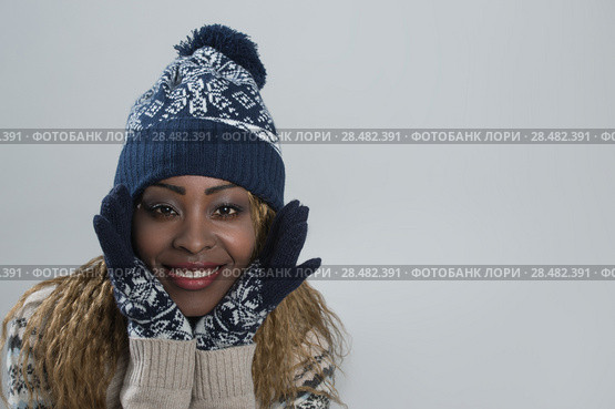 Portrait of african woman on gray background wearing woolen accessories. Стоковое фото, фотограф Kirill Kedrinskiy / Ingram Publishing / Фотобанк Лори