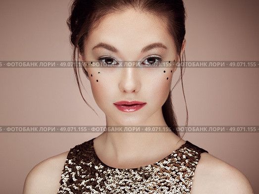 Portrait of beautiful young woman in a shiny golden dress. Brunette girl. Perfect make-up. Freckles. Стоковое фото, агентство Ingram Publishing / Фотобанк Лори
