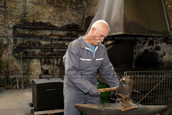 portrait of blacksmith forging metal. Стоковое фото, агентство Ingram Publishing / Фотобанк Лори